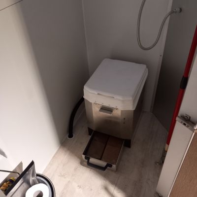 Das Bild zeigt eine Trockentoilette, die im König Anhänger X-Trailer eingebaut wurde. Die geruchsfreie und umweltfreundliche Lösung sorgt für maximale Unabhängigkeit auf Camping- und Outdoor-Abenteuern und ist ab Werk bestellbar bei König