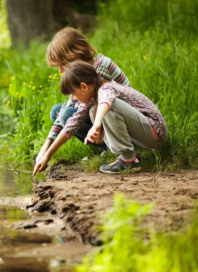 Kinder vom Waldkindergarten sind in der Natur und spielen am Wasser. Waldkindergärten können naturfreundliche Komposttoiletten verwenden.