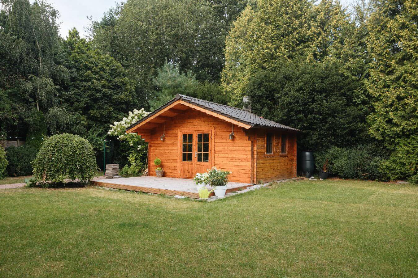 Ein idyllischer Garten mit einem Holz Haus, das eine Komposttoilette integriert hat – optimal für umweltbewusste Gartenliebhaber.