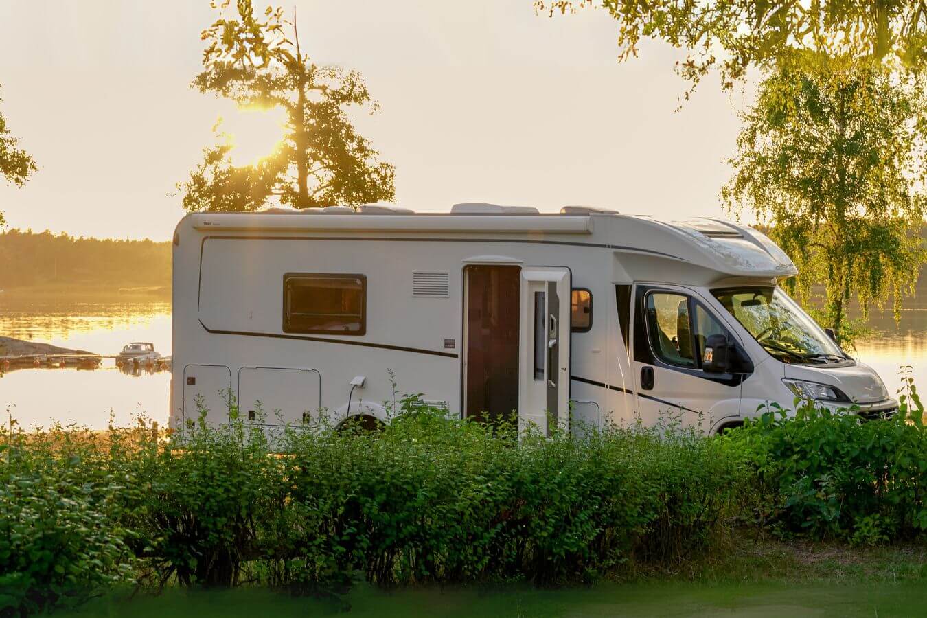 Ein Wohnmobil parkt an einem malerischen See bei Sonnenuntergang, ausgestattet mit einer Komposttoilette im Innenraum für umweltfreundliches Reisen und Autarkie unterwegs.