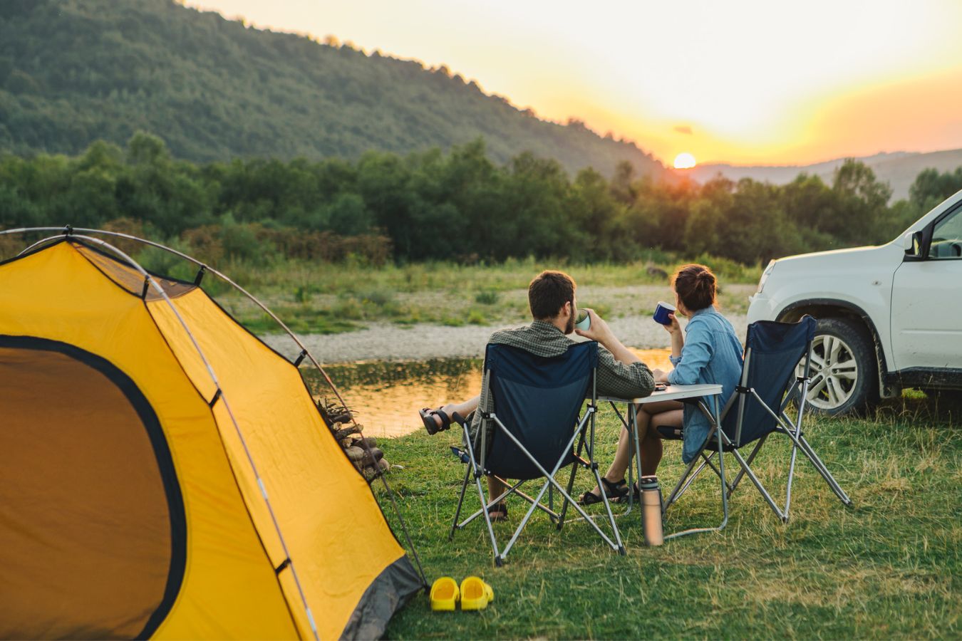 Ein Paar sitzt beim Camping an einem Sumpfgebiet in der Natur. Zum unabhängigen zelten eignet sich eine Trockentoilette dort optimal. Dieses Foto stellt die Freiheit und Emotionen dar.