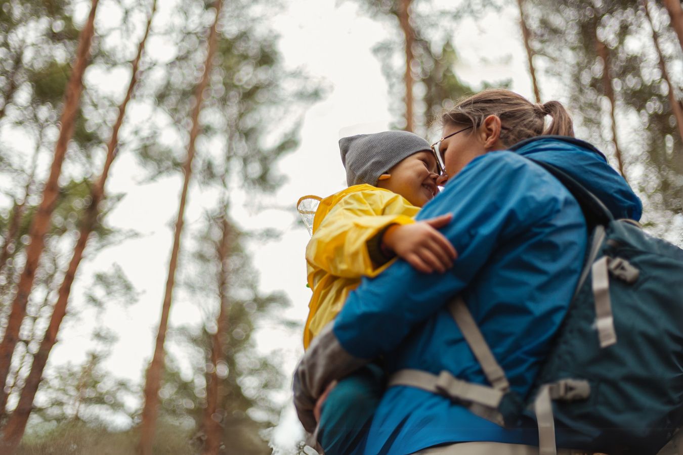 Die Darstellung zeigt eine Mutter mit ihrem fröhlichen Kind auf dem Arm im Wald. Es signalisiert, dass man auch mitten im Wald keine Einschränkungen hat und eine Komposttoilette nutzen kann.